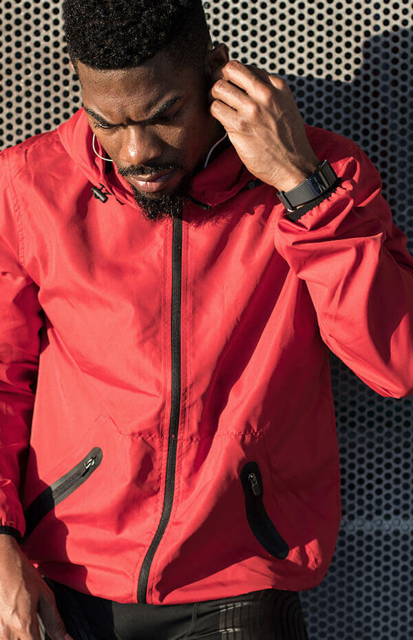 A man in red jacket touching his head.