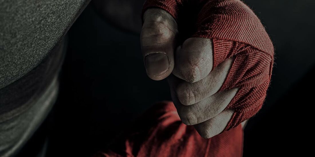 A person wearing red and white gloves holding one hand up to their face.