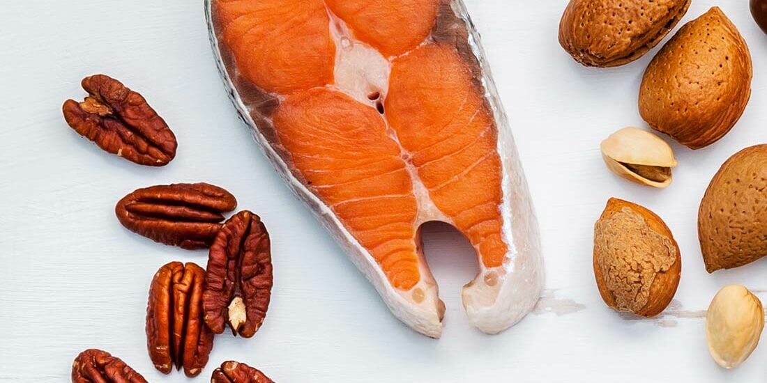 A piece of salmon next to nuts and almonds.