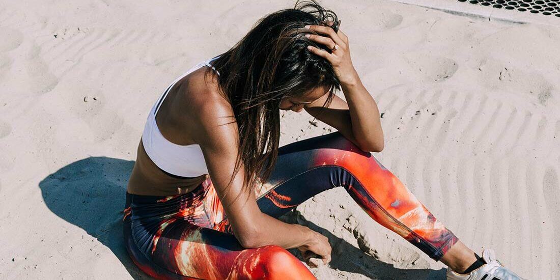 A woman sitting on the beach in yoga pants