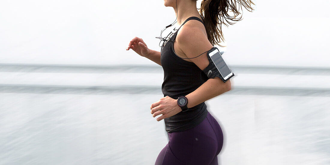 A woman running on the beach with her phone