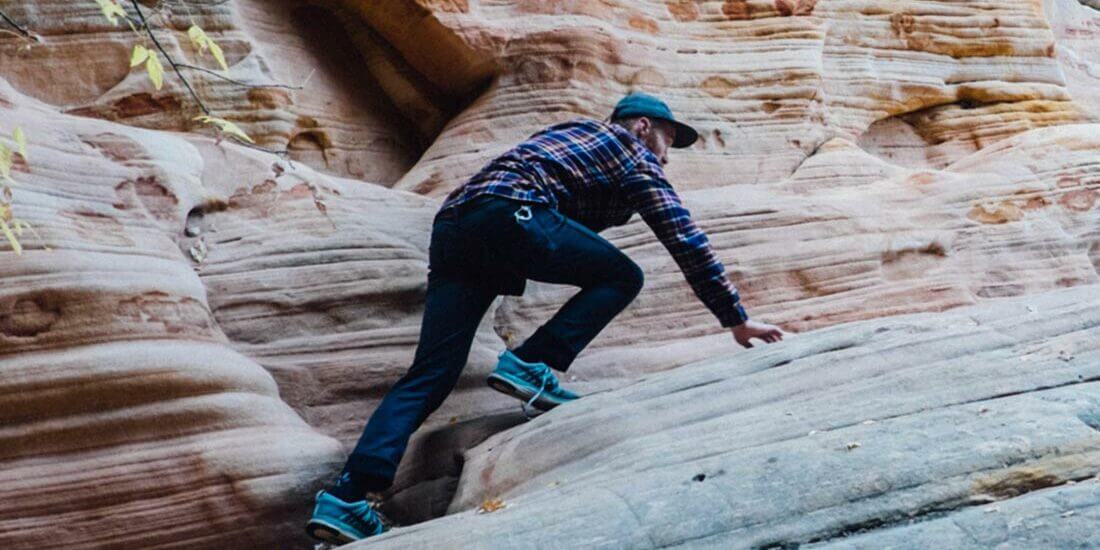 A man riding a skateboard down the side of a rock wall.