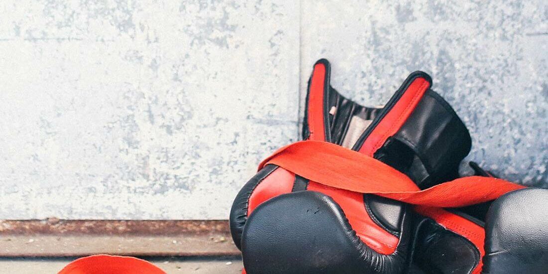 A pair of boxing gloves with red laces on the ground.