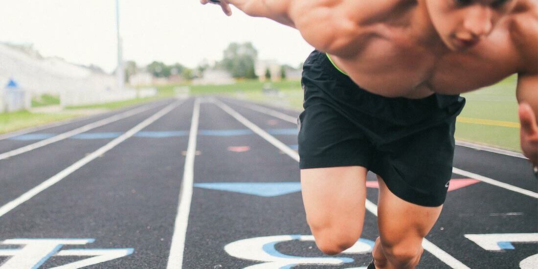 A man running on the track with no shirt