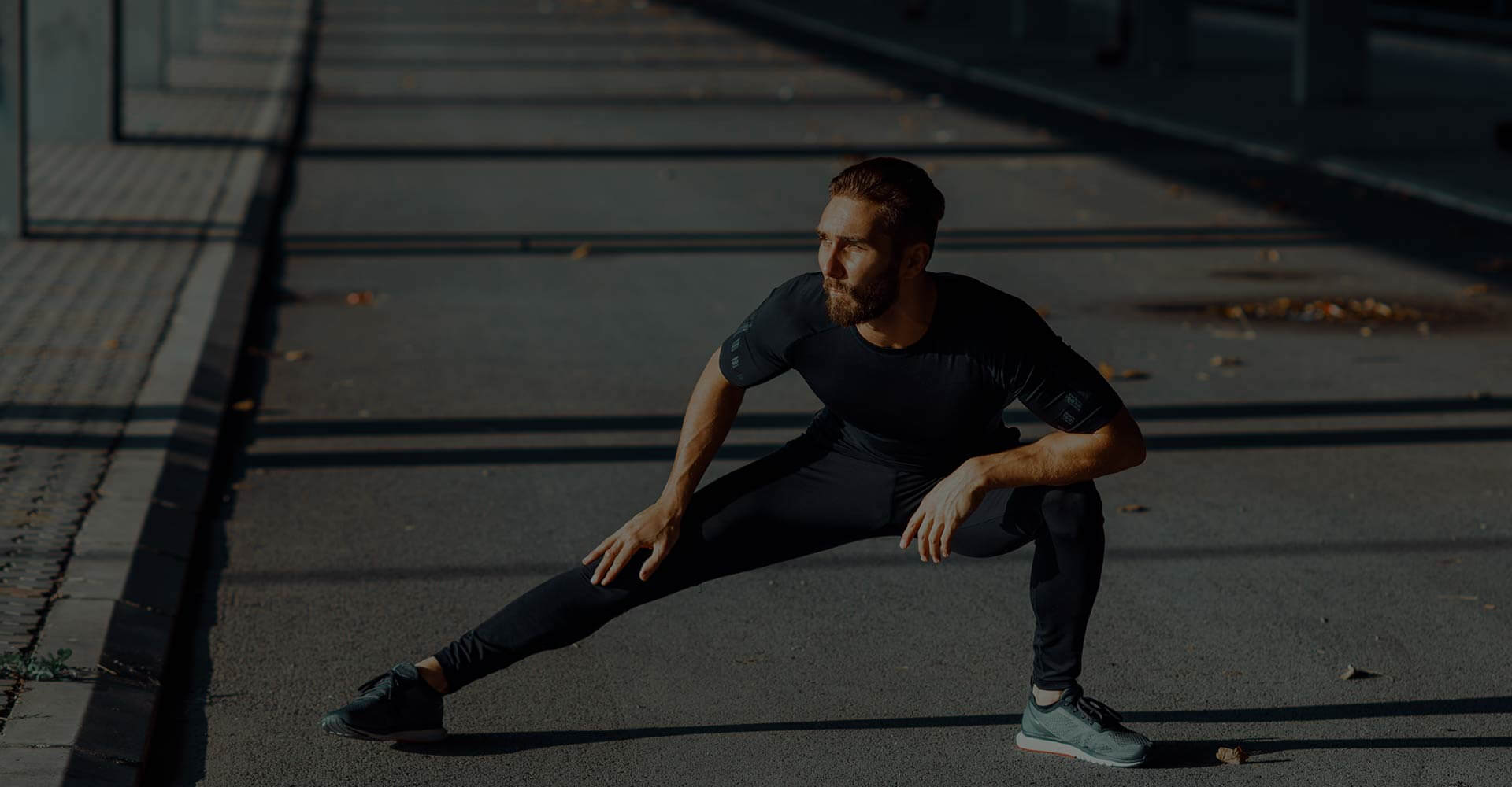 A man stretching his legs on the street.