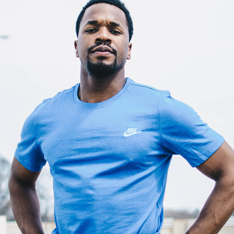 A man in blue shirt standing next to a building.