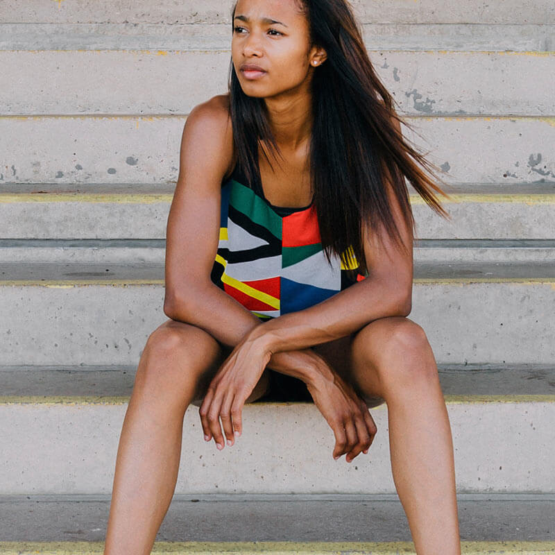 A woman sitting on some steps wearing a colorful top.
