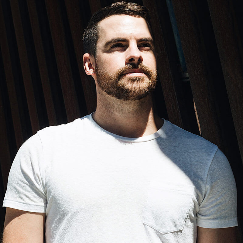 A man with a beard and mustache wearing white shirt.