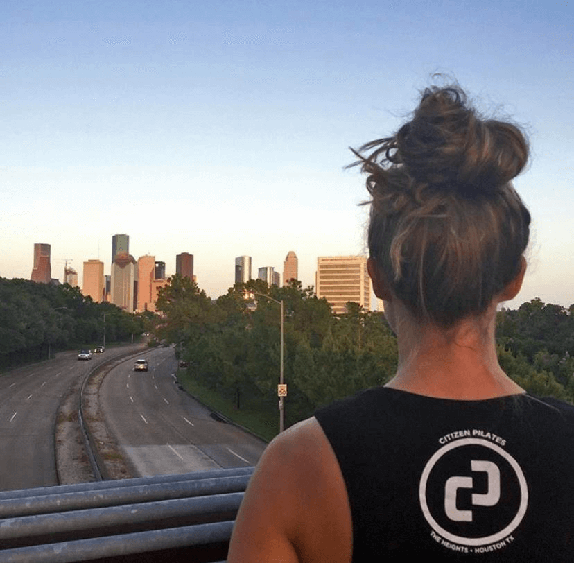 Instructor overlooking the Houston skyline, symbolizing growth, ambition, and Citizen Pilates’ forward-focused vision.